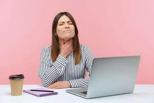 Emotional young woman sitting and working on office with pink background.