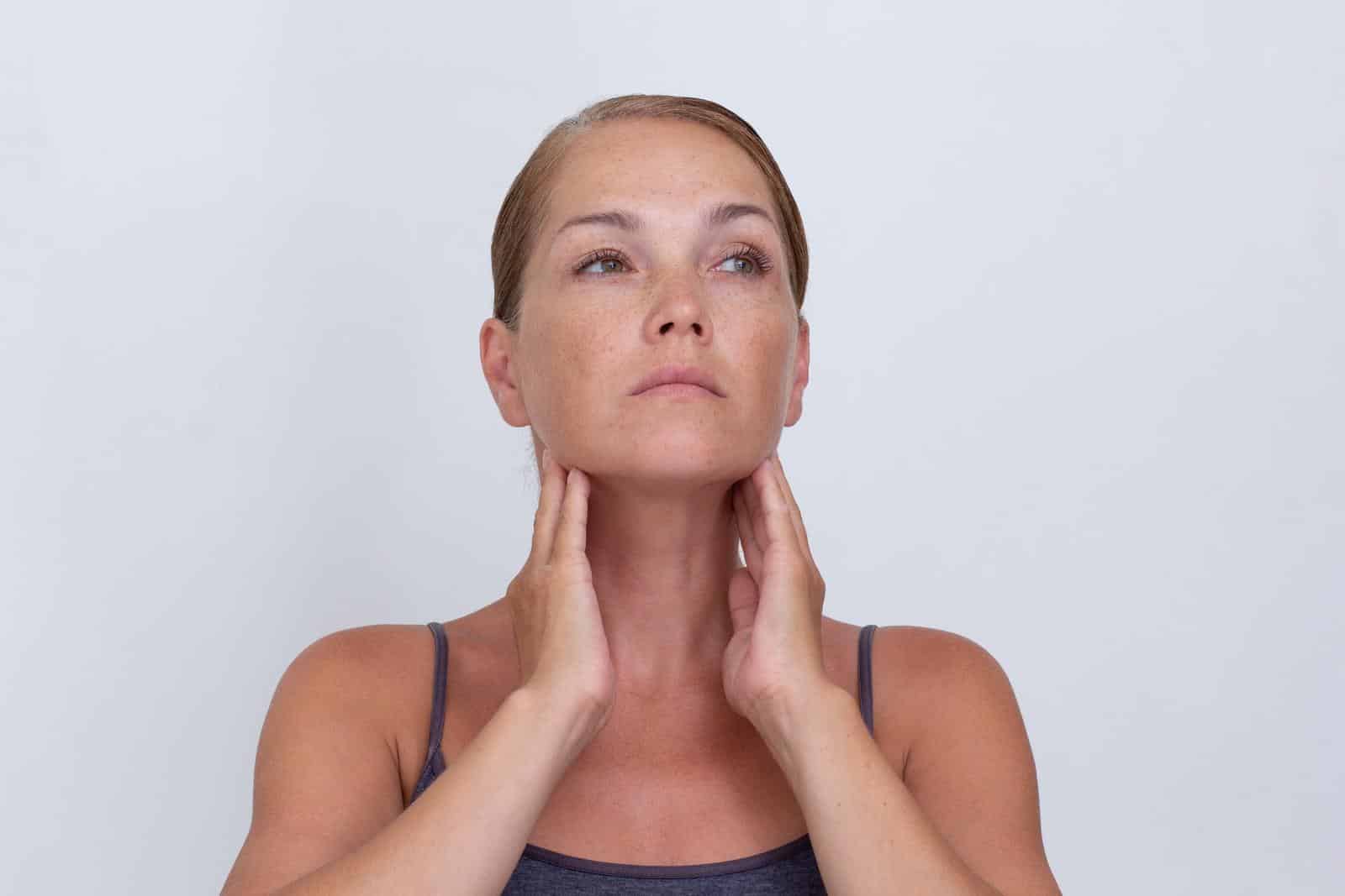 Portrait of woman examining lymph nodes on neckon white background